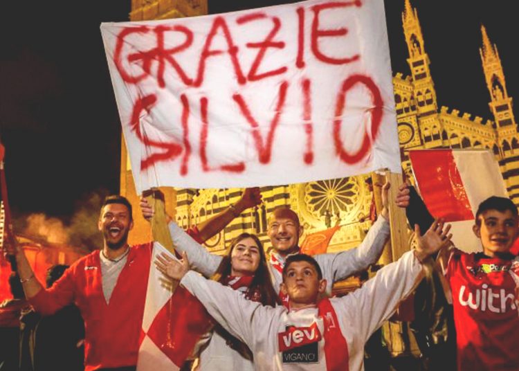 Warga Monza membawa poster Silvio Berlusconi yang berambisi meraih scudetto atau juara Serie A Liga Italia dan berlaga ke Liga Champions musim depan. (net)
