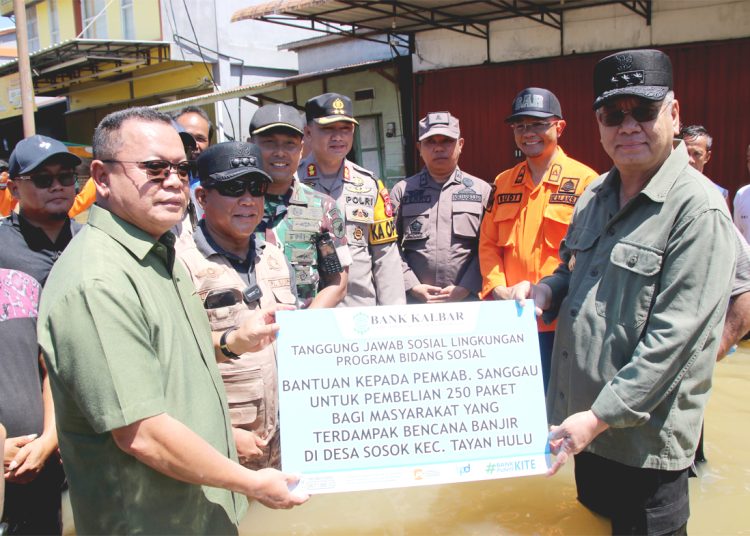 Dirut Bank Kalbar, Rokidi (kiri) didampingi Pj Gubernur Kalbar, Harisson menyerahkan bantuan untuk korban banjir kepada Pemkab Kabupaten Sanggau. (ist)